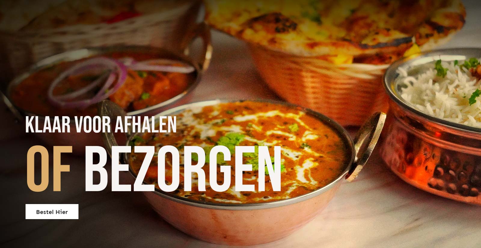 Verschillende Indiase gerechten geserveerd in koperen kommen en manden bij Anmool Restaurant