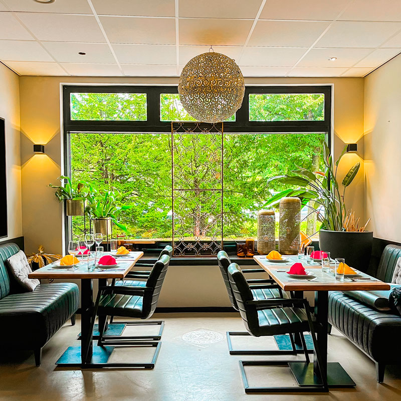 Modern dining area in Anmool Restaurant with large windows and comfortable seating